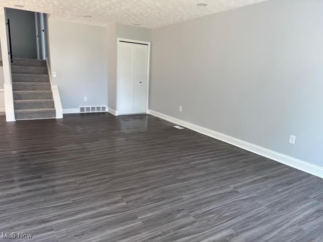 275 Butternut Ln, Berea, OH 44017 - empty room with dark wood-type flooring, stairway, and a textured ceiling