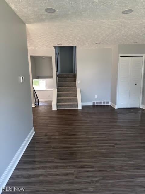 275 Butternut Ln, Berea, OH 44017 - unfurnished living room with a textured ceiling, dark wood-style floors, and stairs