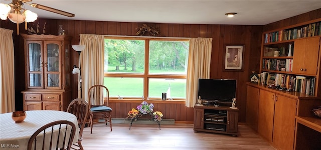 593 Furnace Rd, Conneaut, OH 44030 - living area featuring baseboard heating, light wood-type flooring, wood walls, and a ceiling fan