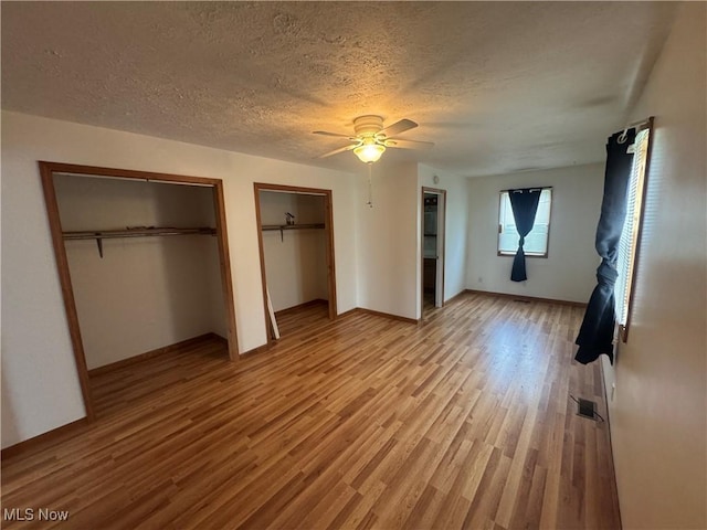 1015 Belford St, Caldwell, OH 43724 - unfurnished bedroom featuring two closets, light wood-style floors, a textured ceiling, and ceiling fan