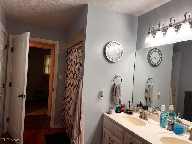67682 Morristown Flushing Rd, Belmont, OH 43718 - full bathroom with double vanity, a textured ceiling, and wood finished floors