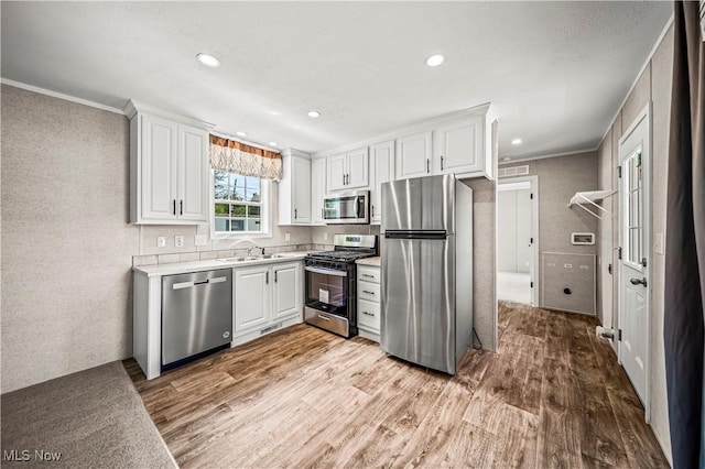 8323 Eagle Rd Unit 42, Kirtland, OH 44094 - kitchen featuring stainless steel appliances, wood finished floors, light countertops, white cabinets, and crown molding