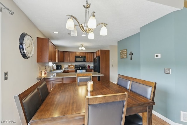 91 Falling Water Cir, Munroe Falls, OH 44262 - kitchen with black appliances, a chandelier, a peninsula, brown cabinetry, and light countertops