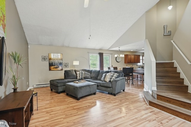 91 Falling Water Cir, Munroe Falls, OH 44262 - living area with a baseboard heating unit, stairway, light wood-style flooring, a chandelier, and high vaulted ceiling