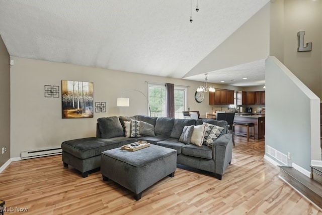 91 Falling Water Cir, Munroe Falls, OH 44262 - living room featuring a baseboard radiator, light wood-style floors, a chandelier, a textured ceiling, and a high ceiling