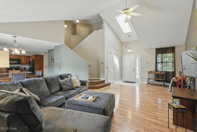 91 Falling Water Cir, Munroe Falls, OH 44262 - living room featuring high vaulted ceiling, a skylight, light wood finished floors, a ceiling fan, and a chandelier