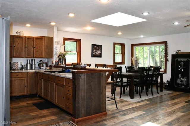 5041 W S Range Rd, Salem, OH 44460 - kitchen featuring a peninsula, a skylight, freestanding refrigerator, a kitchen breakfast bar, and dark wood-style flooring