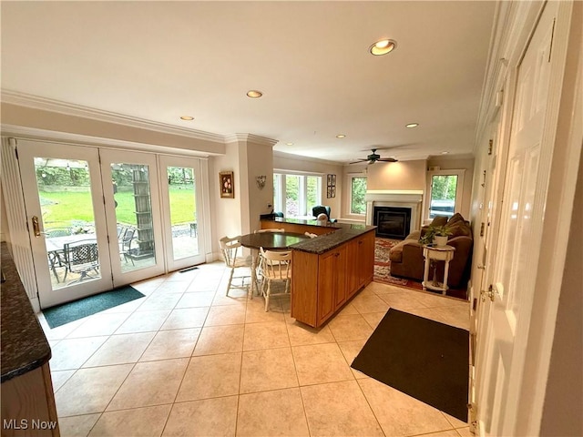 15217 Fox Run, Chagrin Falls, OH 44022 - kitchen with open floor plan, a glass covered fireplace, light tile patterned floors, brown cabinetry, and ornamental molding