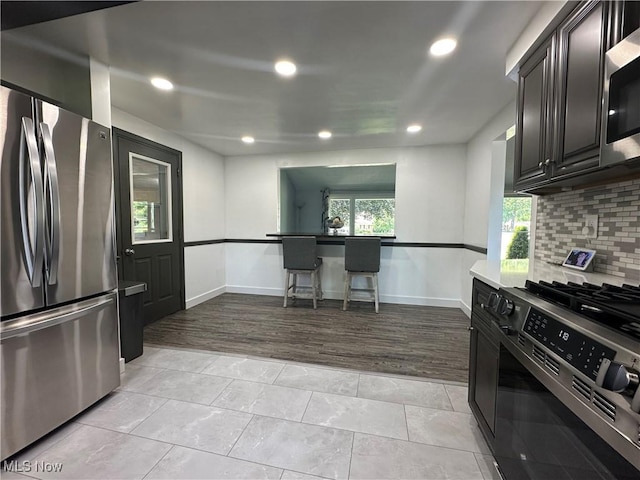 3005 Chaucer Dr NE, Canton, OH 44721 - kitchen with stainless steel appliances, decorative backsplash, recessed lighting, light tile patterned floors, and dark cabinets
