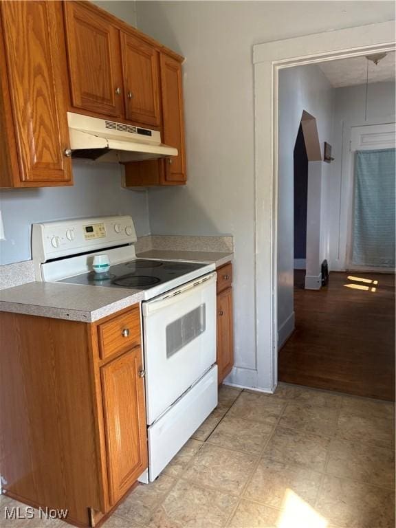 11 Front St, Rittman, OH 44270 - kitchen with electric range, under cabinet range hood, brown cabinetry, and light countertops