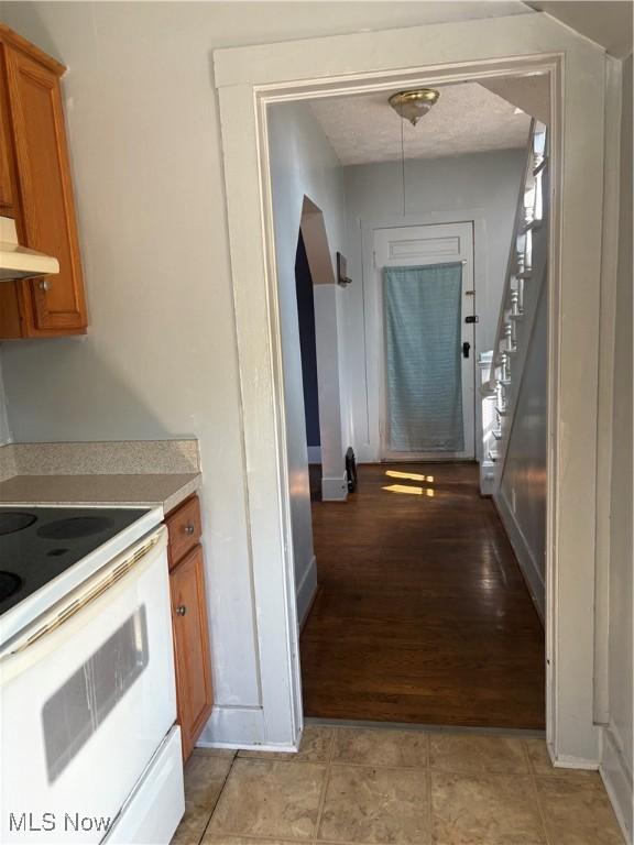 11 Front St, Rittman, OH 44270 - kitchen featuring white electric range, light countertops, brown cabinetry, under cabinet range hood, and light wood-type flooring