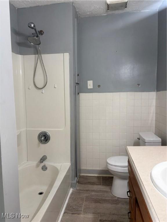 11 Front St, Rittman, OH 44270 - bathroom featuring tile walls, vanity, shower / washtub combination, wood finished floors, and a textured ceiling