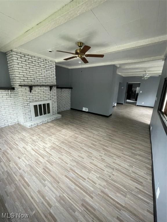 3351 E 65th St, Cleveland, OH 44127 - unfurnished living room with beamed ceiling, a brick fireplace, ceiling fan, and wood finished floors