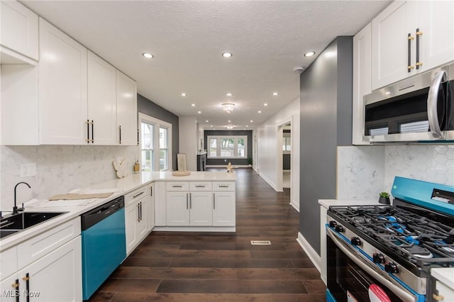 10310 Thrush Ave, Cleveland, OH 44111 - kitchen with appliances with stainless steel finishes, a peninsula, white cabinetry, recessed lighting, and dark wood finished floors
