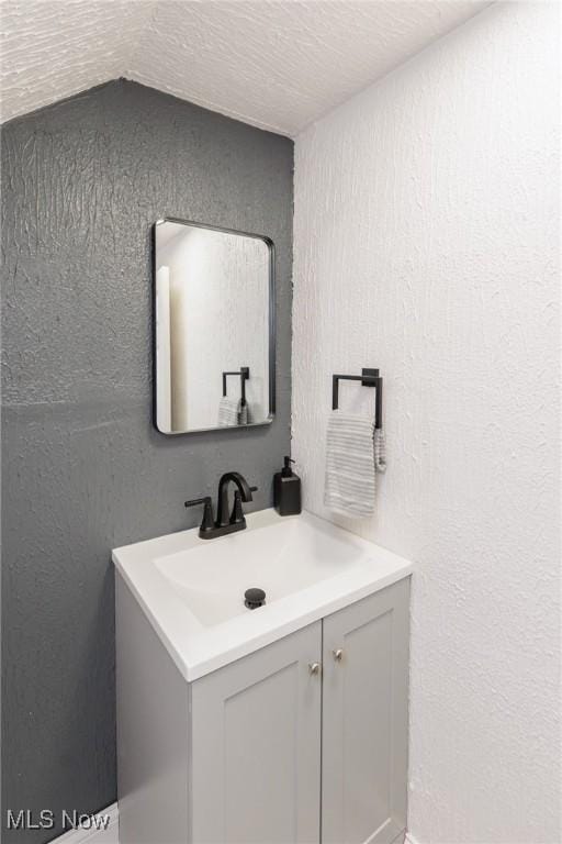 10310 Thrush Ave, Cleveland, OH 44111 - bathroom featuring vanity, a textured wall, and lofted ceiling