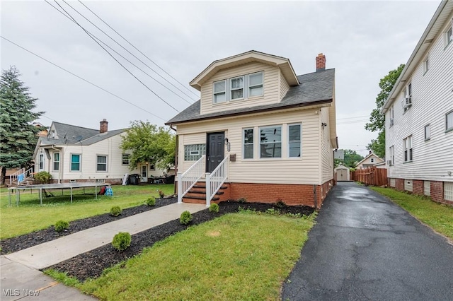 10310 Thrush Ave, Cleveland, OH 44111 - bungalow-style home with a trampoline, a chimney, entry steps, roof with shingles, and asphalt driveway