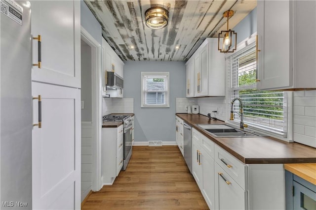 6207 Dartworth Dr, Parma, OH 44129 - kitchen featuring appliances with stainless steel finishes, butcher block counters, light wood-style floors, decorative backsplash, and white cabinets