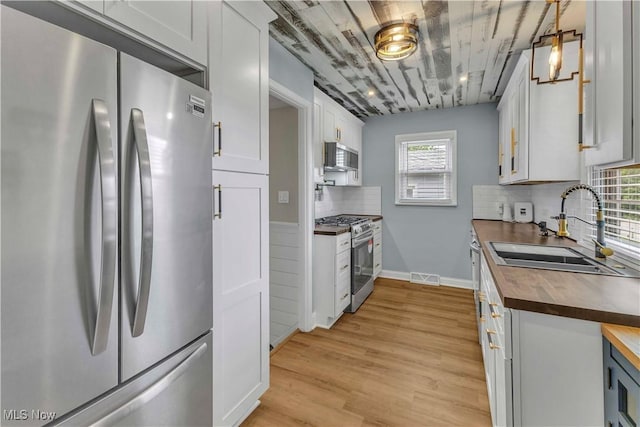6207 Dartworth Dr, Parma, OH 44129 - kitchen with appliances with stainless steel finishes, butcher block countertops, light wood-style floors, tasteful backsplash, and white cabinetry