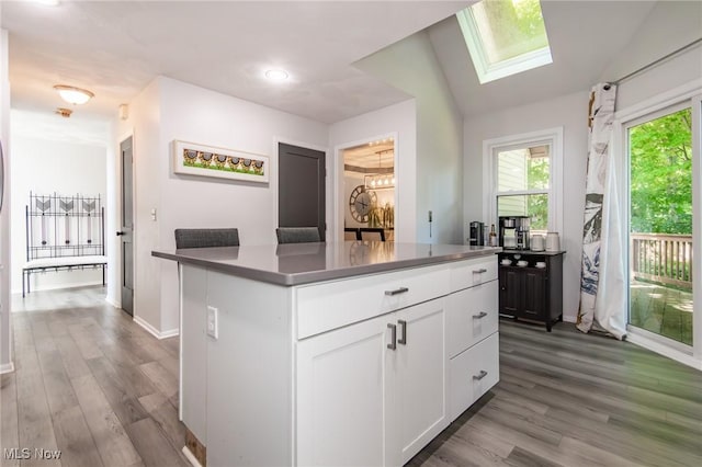5710 Cardinal Dr, Mentor, OH 44060 - kitchen with a skylight, white cabinetry, wood finished floors, and a kitchen island