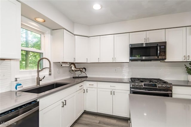 5710 Cardinal Dr, Mentor, OH 44060 - kitchen with stainless steel appliances, white cabinets, decorative backsplash, light wood finished floors, and recessed lighting