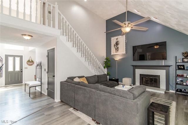 5710 Cardinal Dr, Mentor, OH 44060 - living room with a ceiling fan, wood finished floors, high vaulted ceiling, a tile fireplace, and stairway