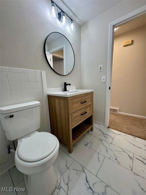 233 Kennedy St, Louisville, OH 44641 - bathroom with vanity, marble look tile flooring, and a textured ceiling