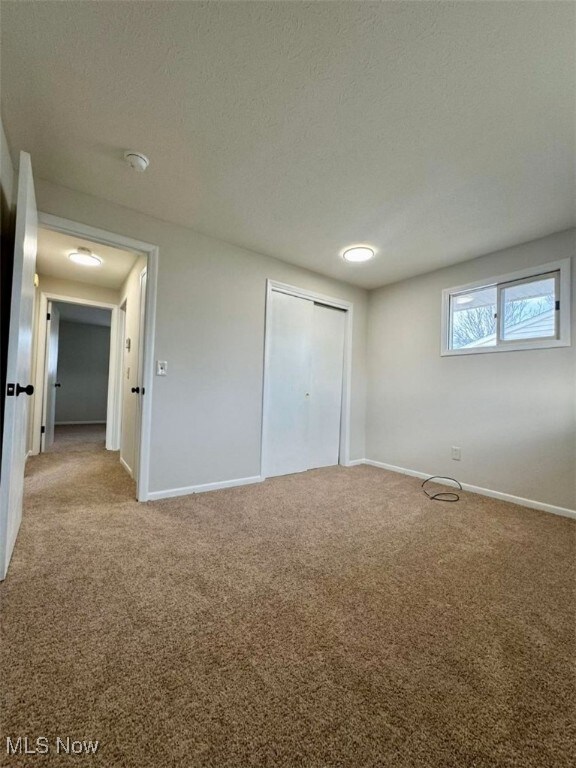 233 Kennedy St, Louisville, OH 44641 - unfurnished bedroom featuring carpet, a closet, and a textured ceiling