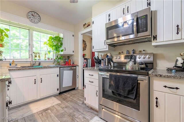 1201 Overlook Dr, Alliance, OH 44601 - kitchen featuring appliances with stainless steel finishes, white cabinetry, light wood-style flooring, and light stone countertops
