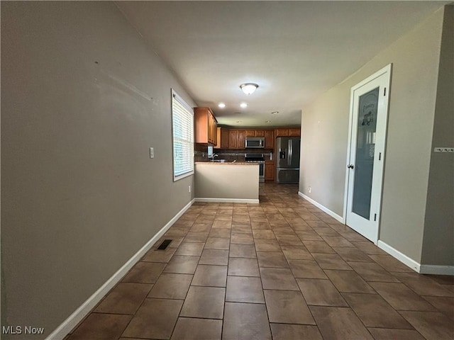 1312 Glennview St NE, Canton, OH 44721 - kitchen with stainless steel appliances, a peninsula, brown cabinets, dark tile patterned floors, and backsplash