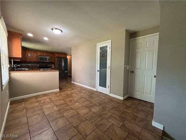 1312 Glennview St NE, Canton, OH 44721 - kitchen featuring black refrigerator with ice dispenser, stainless steel microwave, recessed lighting, brown cabinetry, and a peninsula