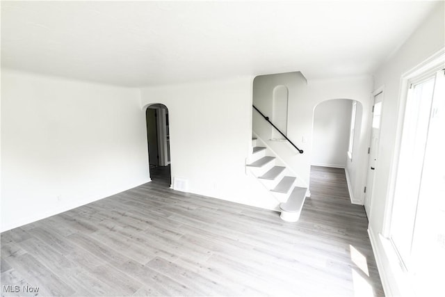 6580 Crossview Rd, Seven Hills, OH 44131 - unfurnished living room with arched walkways, wood finished floors, and stairway