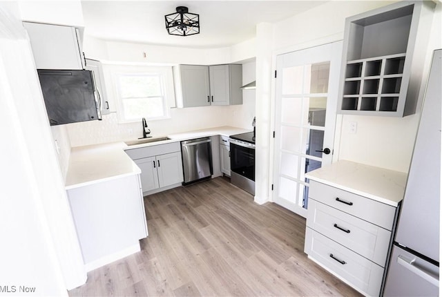 6580 Crossview Rd, Seven Hills, OH 44131 - kitchen featuring appliances with stainless steel finishes, light wood finished floors, light countertops, gray cabinets, and wall chimney range hood