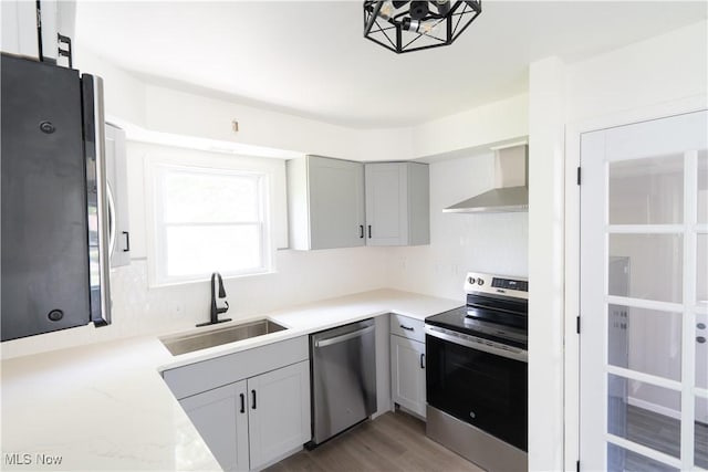 6580 Crossview Rd, Seven Hills, OH 44131 - kitchen featuring appliances with stainless steel finishes, wall chimney range hood, light stone counters, gray cabinetry, and light wood finished floors