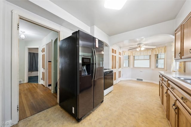 16200 Elsienna Ave, Cleveland, OH 44135 - kitchen featuring stainless steel fridge, range with gas cooktop, arched walkways, ceiling fan, and brown cabinetry