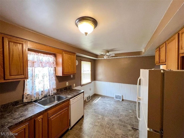 24850 Zeman Ave, Euclid, OH 44123 - kitchen with white appliances, ceiling fan, brown cabinets, dark countertops, and a wainscoted wall