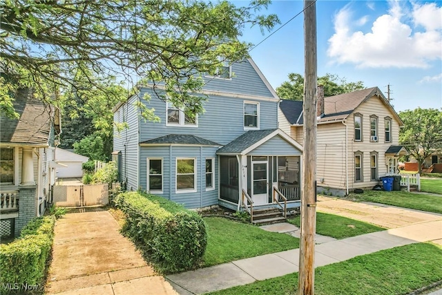 3676 E 69th St, Cleveland, OH 44105 - view of front of home featuring a sunroom, a shingled roof, a front lawn, and a gate