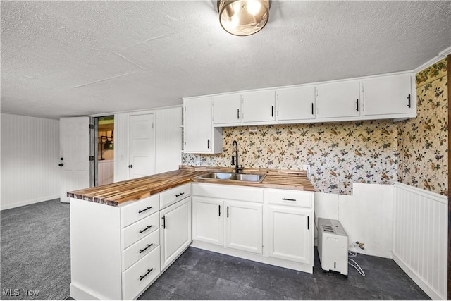 1369 Adelaide Ave SE, Warren, OH 44484 - kitchen featuring butcher block countertops, a textured ceiling, a peninsula, white cabinetry, and wallpapered walls