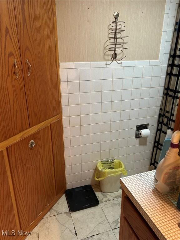 925 Ohio Ave, Mcdonald, OH 44437 - bathroom with marble look tile flooring, tile walls, and vanity