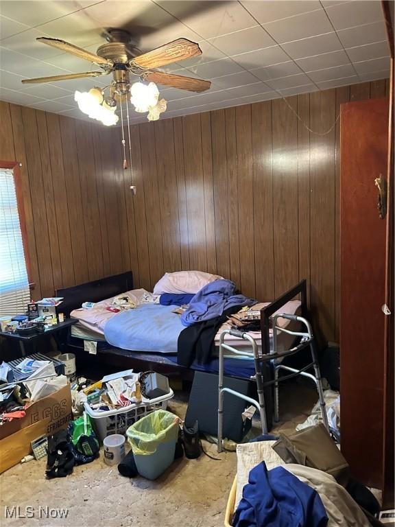 925 Ohio Ave, Mcdonald, OH 44437 - bedroom with wood walls, unfinished concrete floors, and a ceiling fan