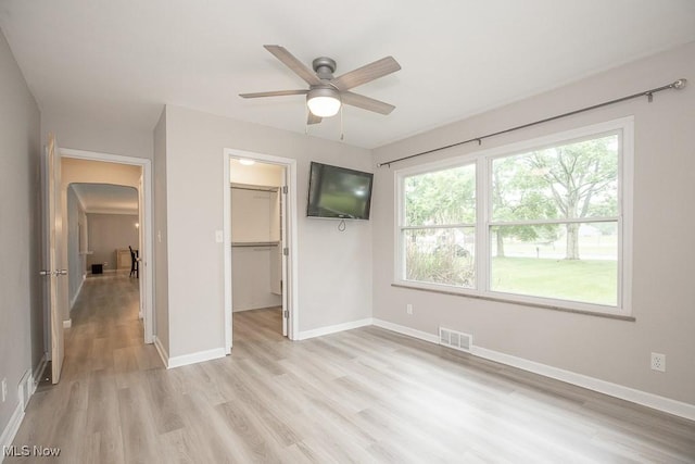 2611 E Pleasant Valley Rd, Seven Hills, OH 44131 - unfurnished bedroom featuring light wood finished floors, a spacious closet, arched walkways, a closet, and ceiling fan