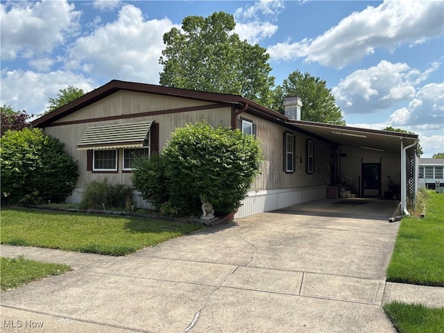 3 Concert Ln, Olmsted Twp, OH 44138 - manufactured / mobile home featuring an attached carport, driveway, a front lawn, and a chimney