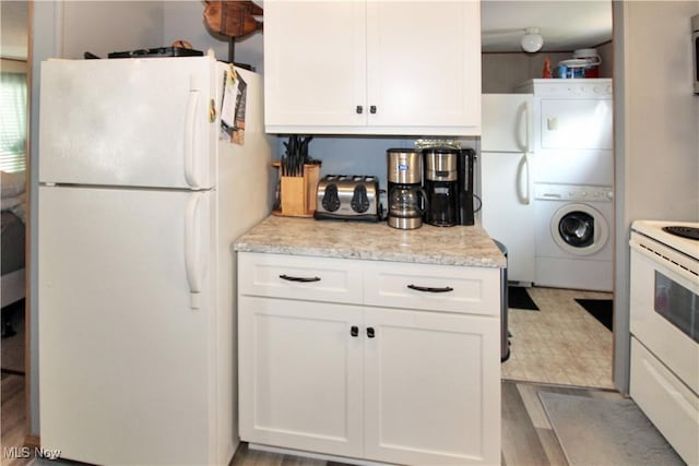 1660 N Compass Ave, Port Clinton, OH 43452 - kitchen featuring white appliances, stacked washer and clothes dryer, white cabinets, and light stone counters