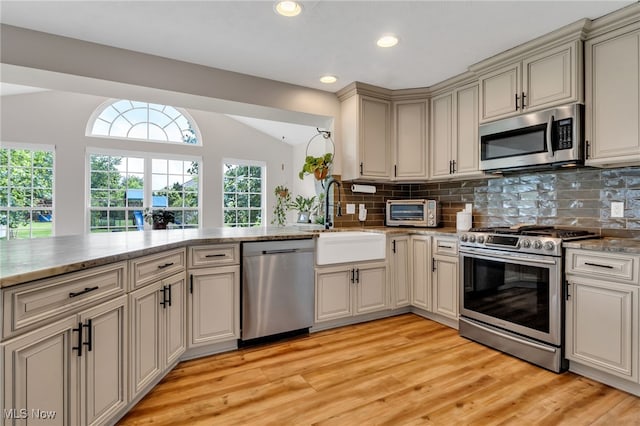 4532 Ridgestone Way, Medina, OH 44256 - kitchen with stainless steel appliances, lofted ceiling, backsplash, light wood finished floors, and cream cabinetry