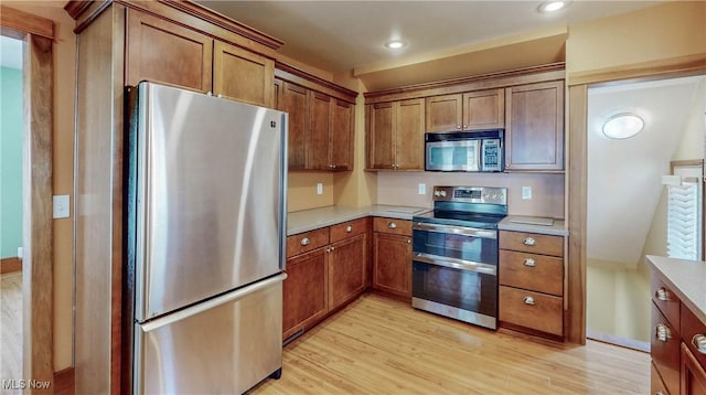 26 Walnut Ct, Mogadore, OH 44260 - kitchen featuring appliances with stainless steel finishes, light wood finished floors, light countertops, brown cabinetry, and recessed lighting