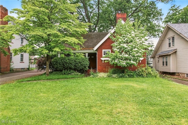 1754 Edgewood St NE, Warren, OH 44483 - view of front of house with a chimney, a front yard, roof with shingles, and brick siding