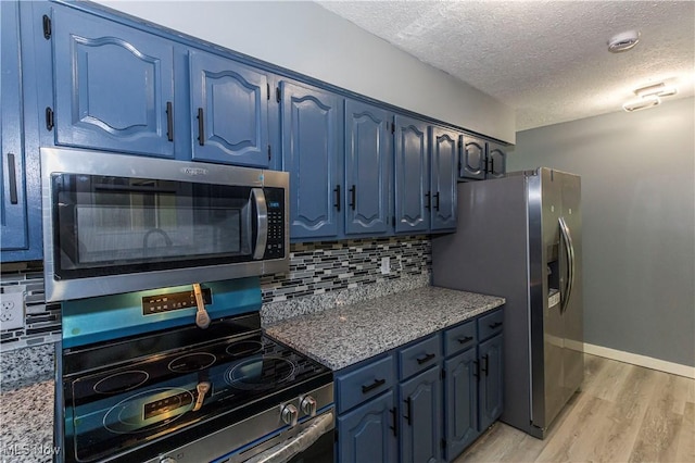 12604 Saint John Ave, Cleveland, OH 44111 - kitchen with stainless steel appliances, blue cabinets, a textured ceiling, light wood-style flooring, and decorative backsplash