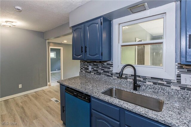 12604 Saint John Ave, Cleveland, OH 44111 - kitchen with dishwashing machine, blue cabinetry, decorative backsplash, light wood-style flooring, and a textured ceiling