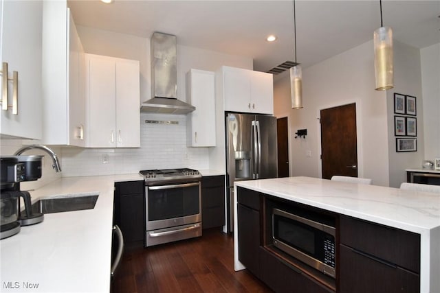 604 Marquardt Ave, Cleveland, OH 44113 - kitchen with appliances with stainless steel finishes, wall chimney exhaust hood, dark wood finished floors, white cabinets, and recessed lighting