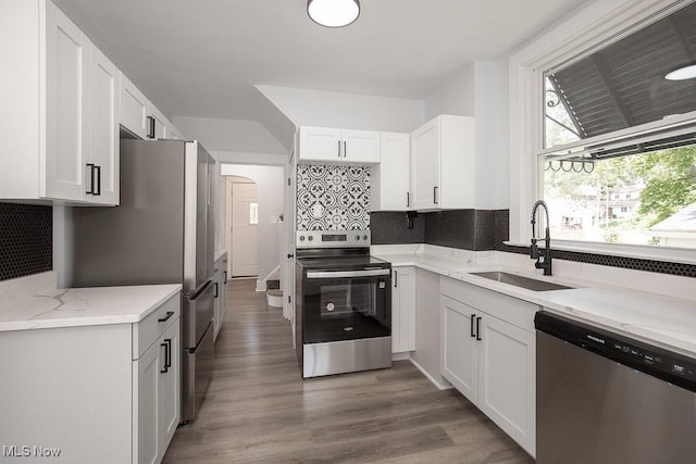 381 Watson St, Akron, OH 44305 - kitchen featuring appliances with stainless steel finishes, backsplash, arched walkways, and white cabinetry