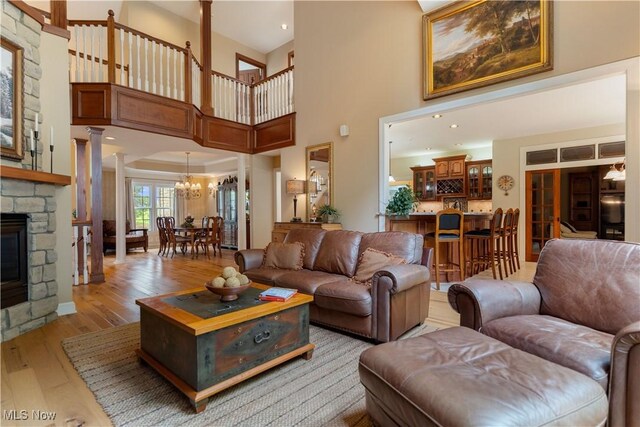 1588 Eagle Watch St NE, Canton, OH 44721 - living area featuring a towering ceiling, decorative columns, a chandelier, light wood finished floors, and a fireplace